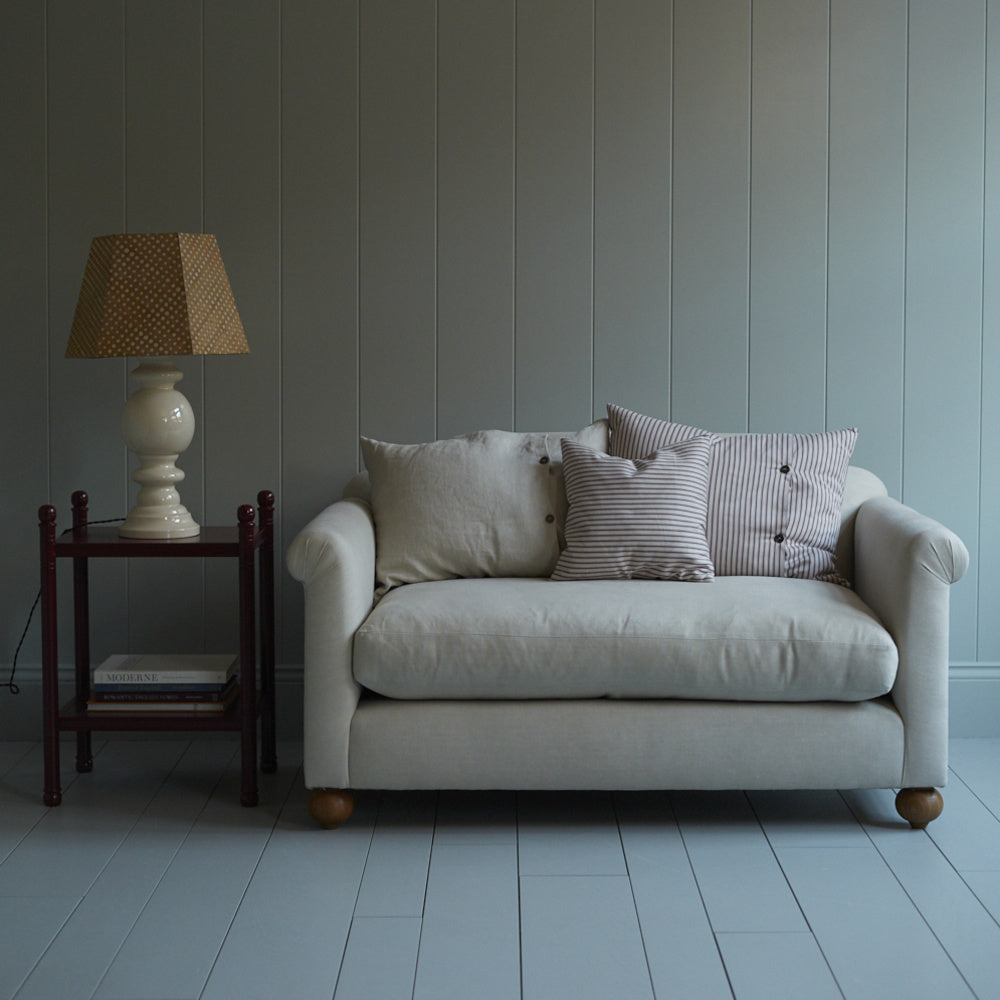 NiX 2-seater sofa with 2 rectangular cushions, 1 square NiX cushion, a red side table, and a white base lamp. - NiX