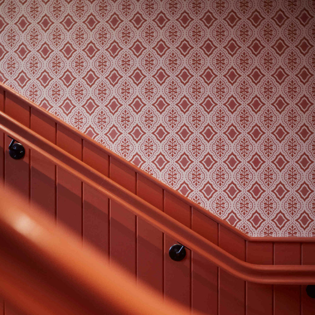 Rhombus wallpaper in Rhubarb and Pink on the wall of the stairs, adding a vibrant design element in our Beaverbrook Village Project