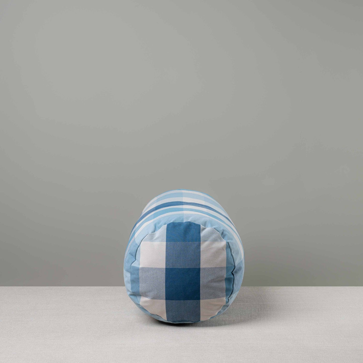 Side View of Bask Bolster Cushion in Checkmate Cotton, Blue - Nicola Harding