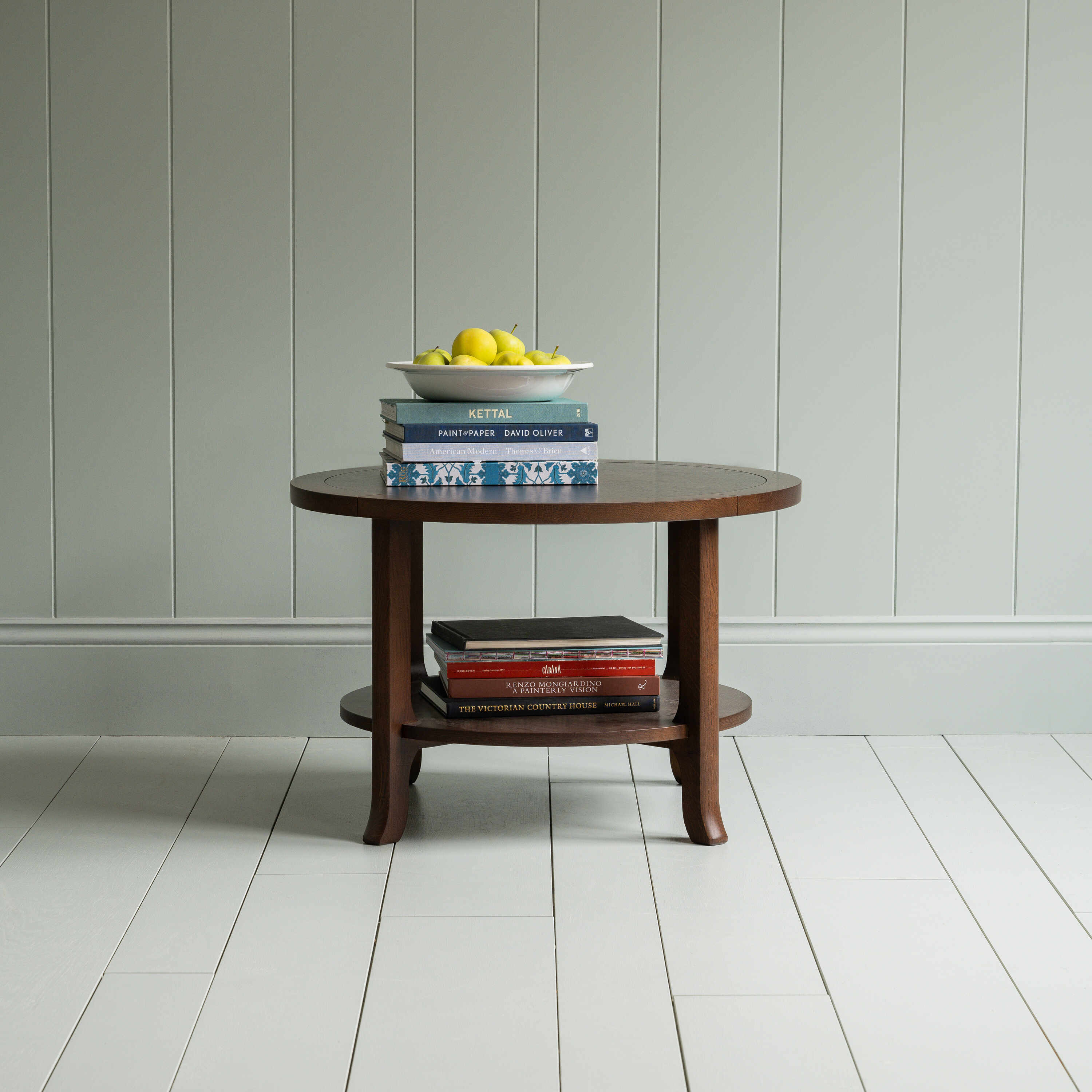 Round Perk coffee table in smoky stained oak with books and a plate of fruits, by Nicola Harding & Co.