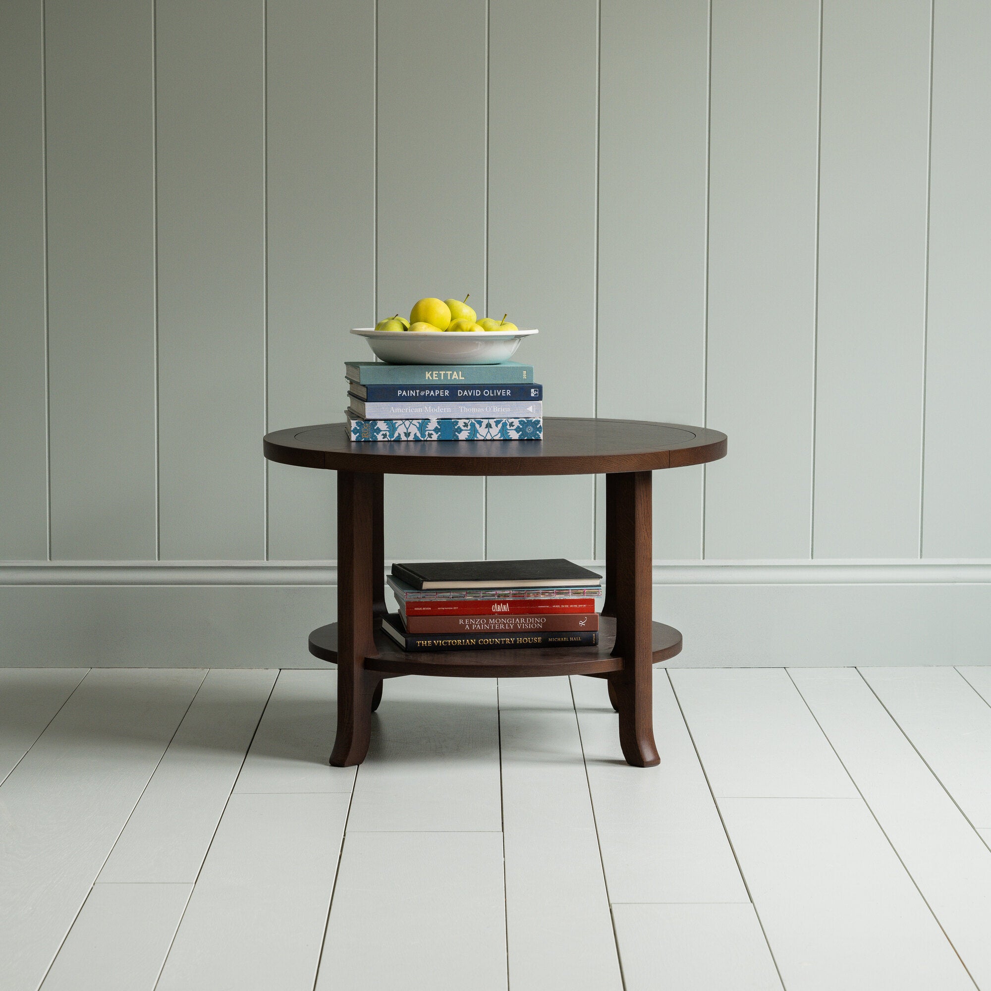 Round Perk coffee table in smoky stained oak with books and a plate of fruits, by Nicola Harding & Co.