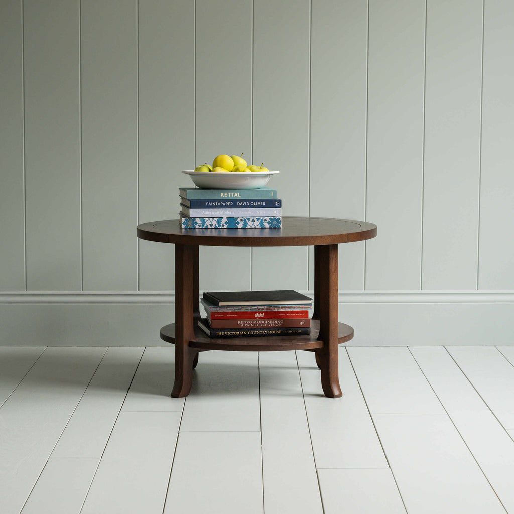 Round Perk coffee table in smoky stained oak with books and a plate of fruits, by Nicola Harding & Co.