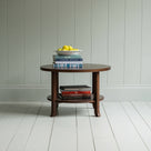 Round Perk coffee table in smoky stained oak with books and a plate of fruits, by Nicola Harding & Co.