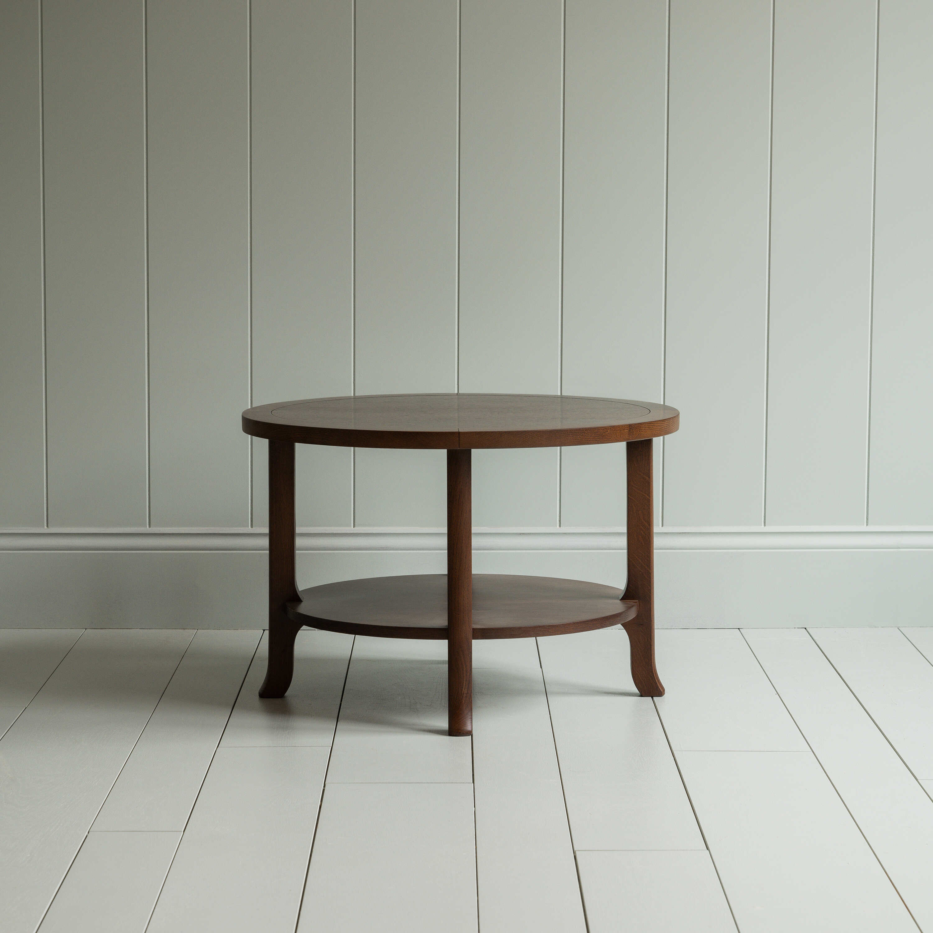 A round wooden coffee table with sturdy wooden base on the wooden floor - By NiX
