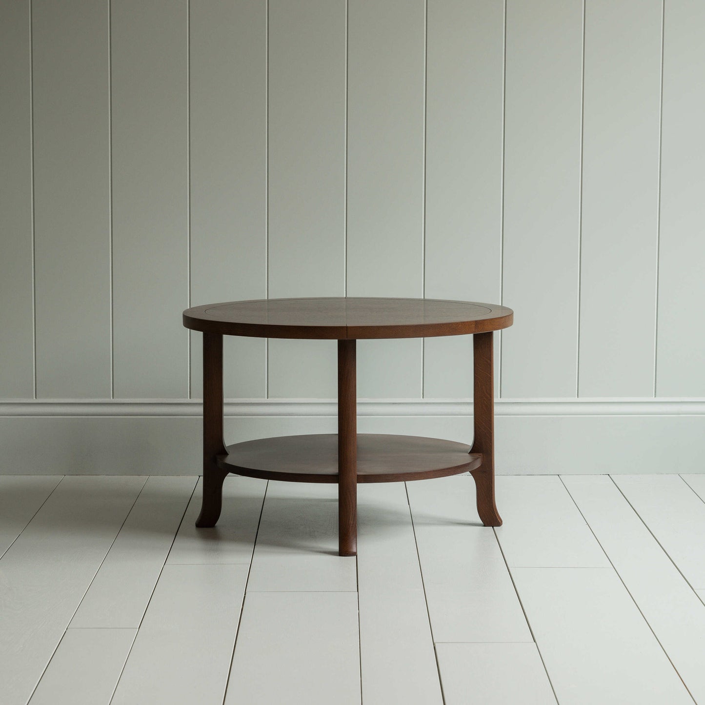A round wooden coffee table with sturdy wooden base on the wooden floor - By NiX