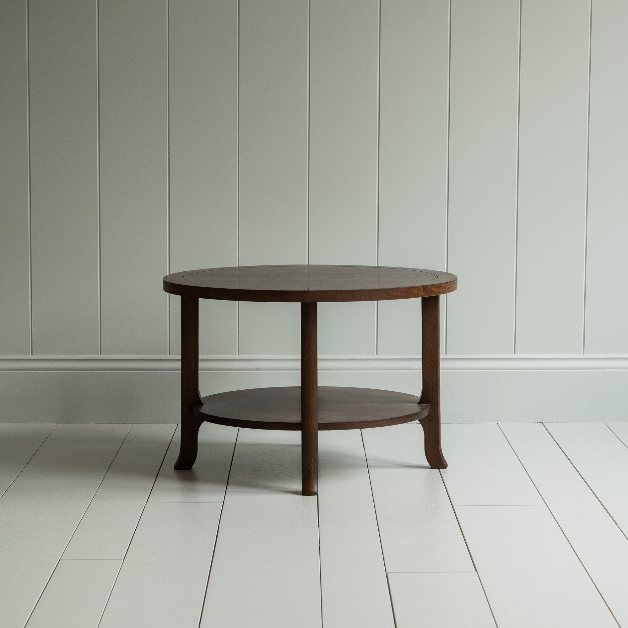 A round wooden coffee table with sturdy wooden base on the wooden floor - By NiX