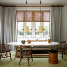 Two Rise Pendant, Brass, (Ceiling Lights) Hanging From Ceiling, Above the Oval Shaped Dining Table With 3 Wooden Chairs in Front of Living Room Window - By NiX