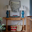 Keepsake Console Table in oiled oak with a drawer, placed in a walkway, adorned with a couple of books and two blue base lamps.