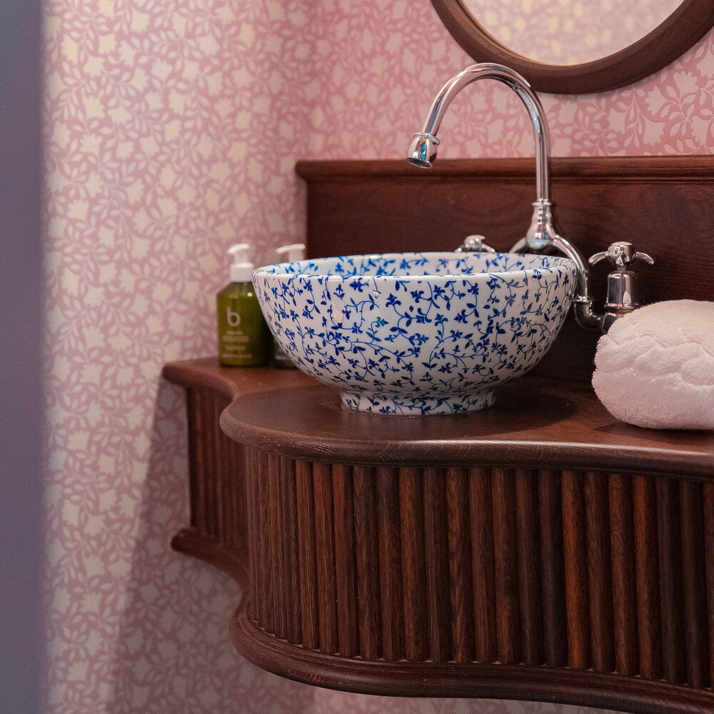Beautiful round basin in a washroom with Ginkgo wallpaper in Rose Pink, designed by (NiX by Nicola Harding & Co.)