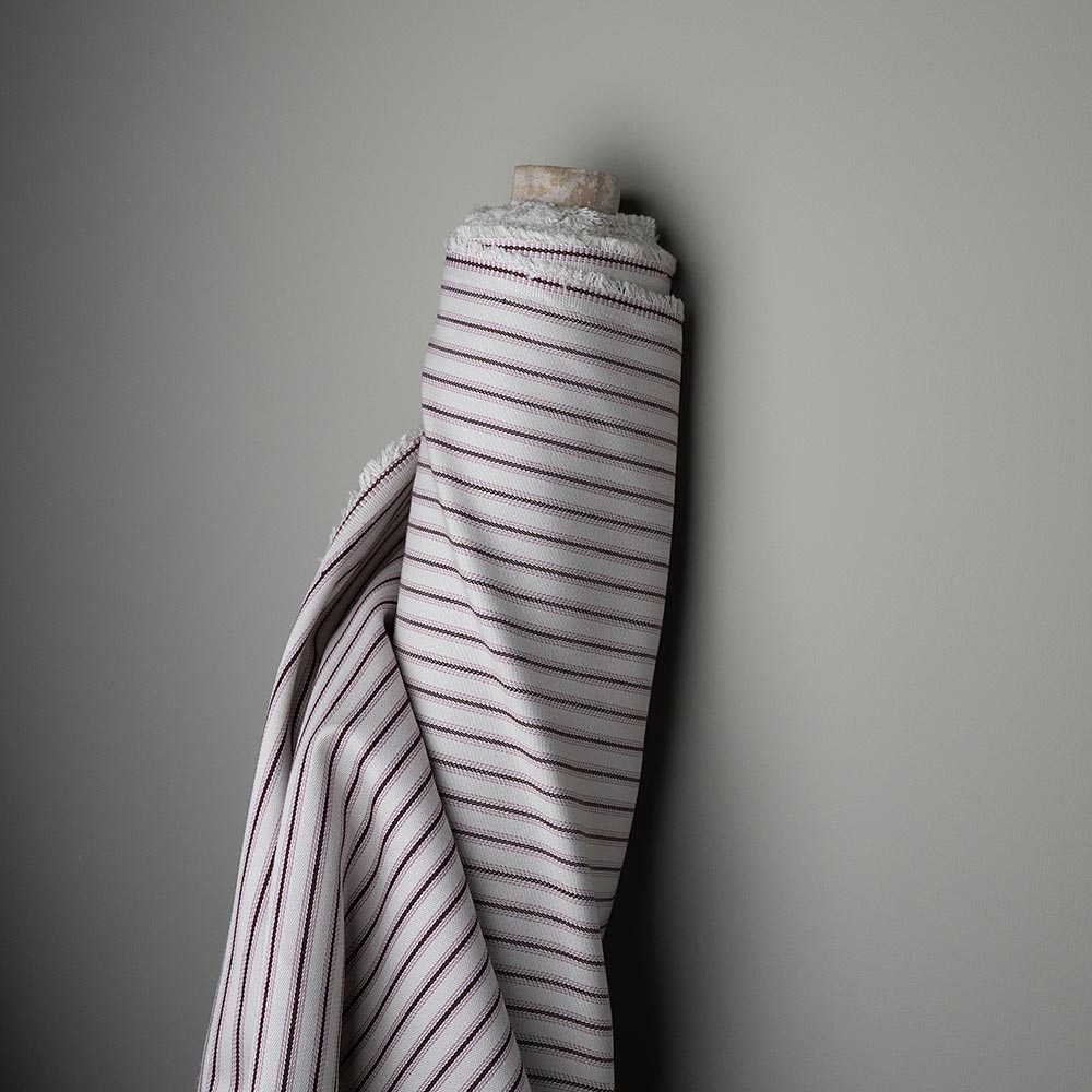A white and red striped fabric Roll hanging on a wall.