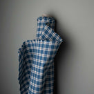 Blue and white checkered cloth decoratively displayed on a wall.
