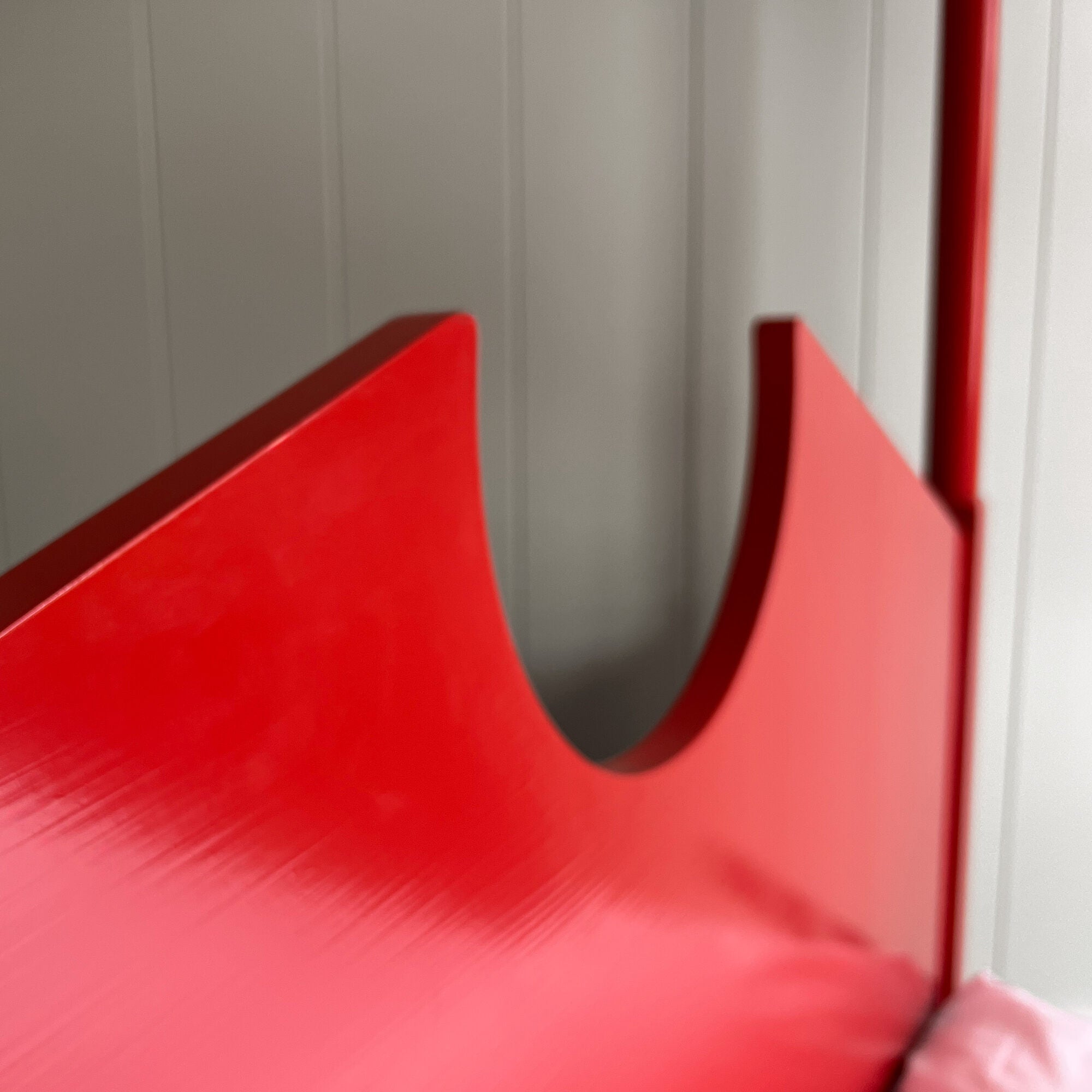 A red metal bed with a white pillow, providing comfort and style to any bedroom decor.