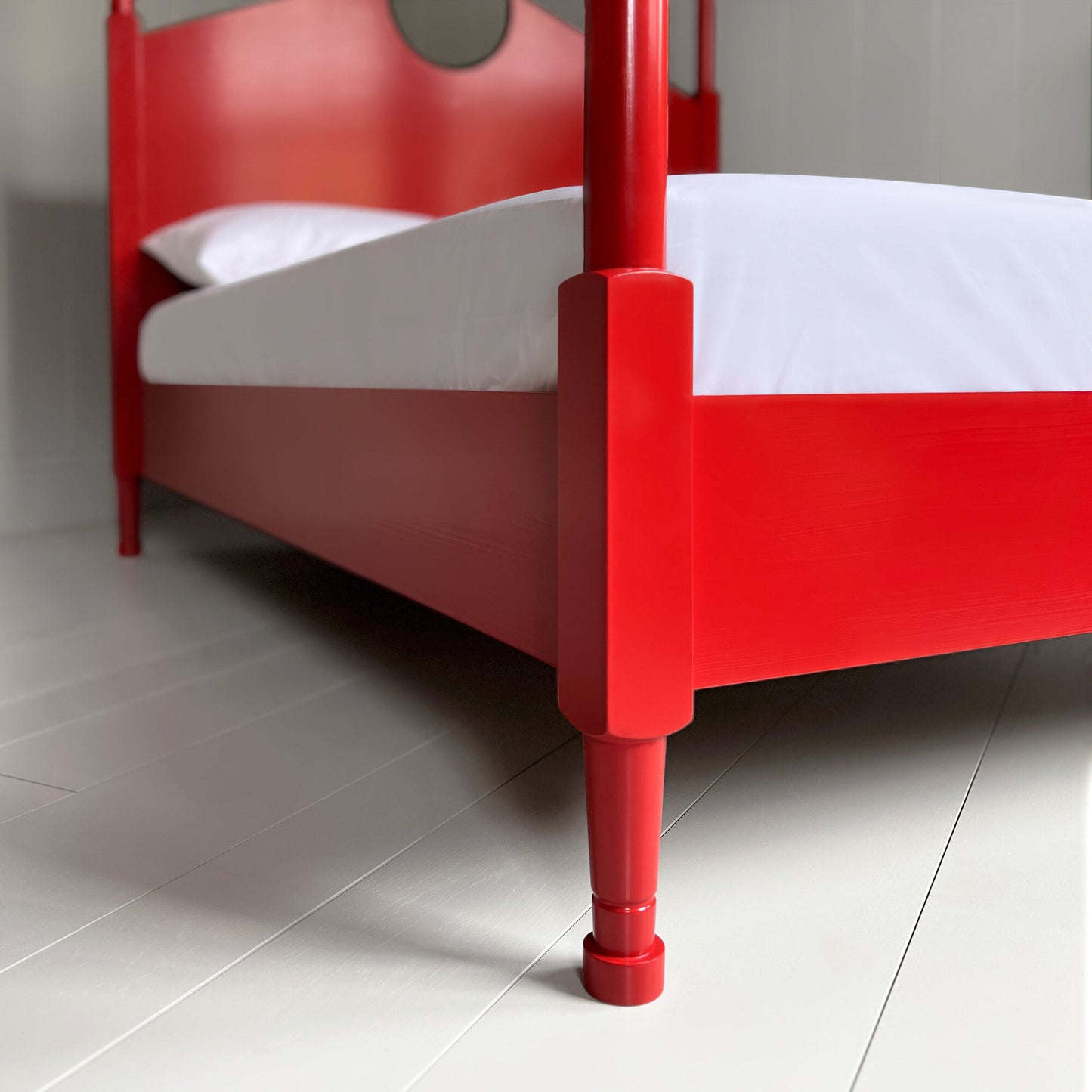A close up of red canopy bed with crisp white sheets, creating a serene and elegant atmosphere.