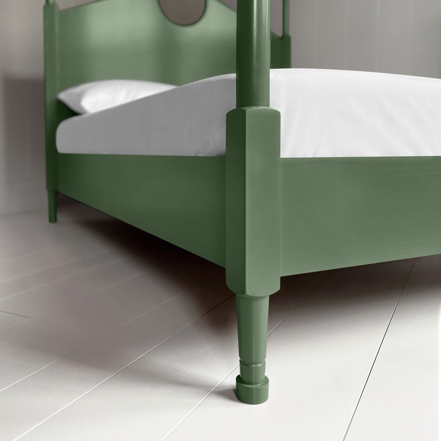 A close up of green canopy bed with crisp white sheets, creating a serene and elegant atmosphere.