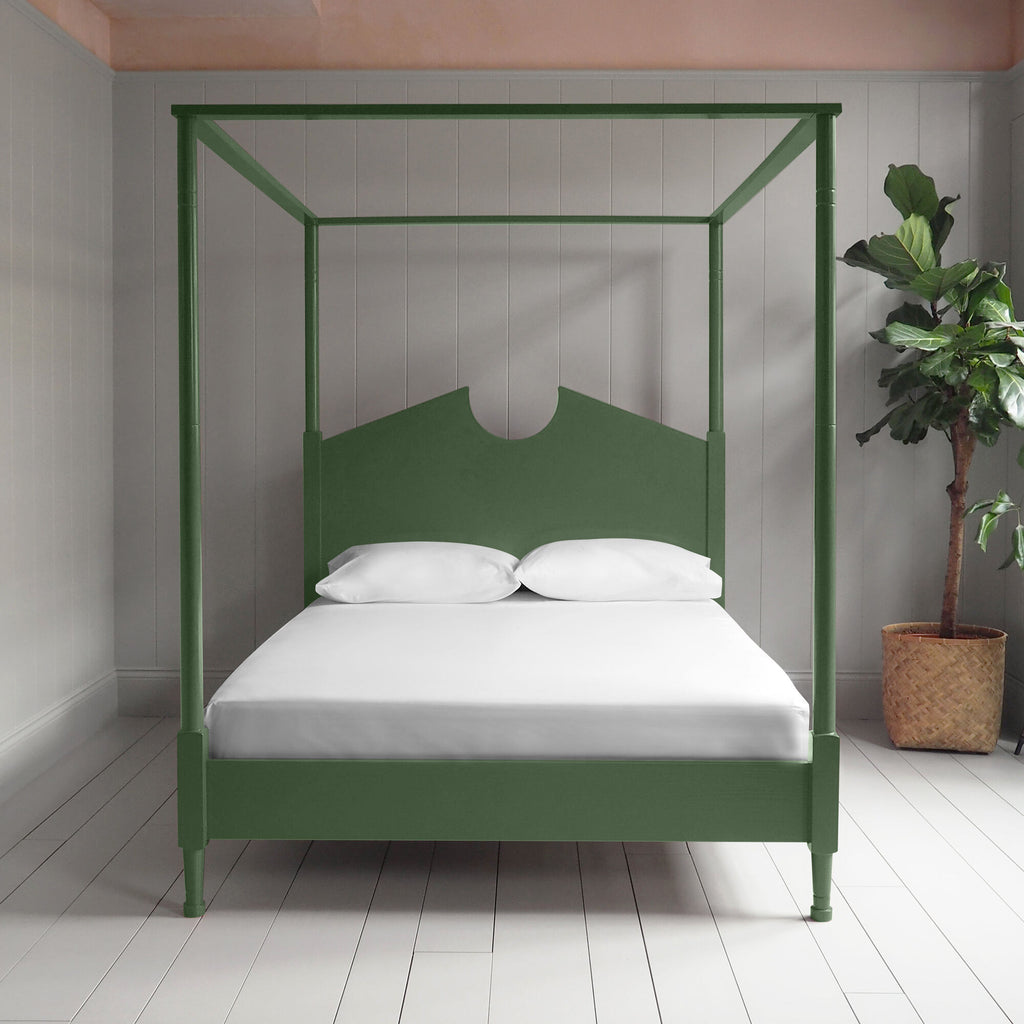 A green canopy bed with crisp white sheets, creating a serene and elegant atmosphere.