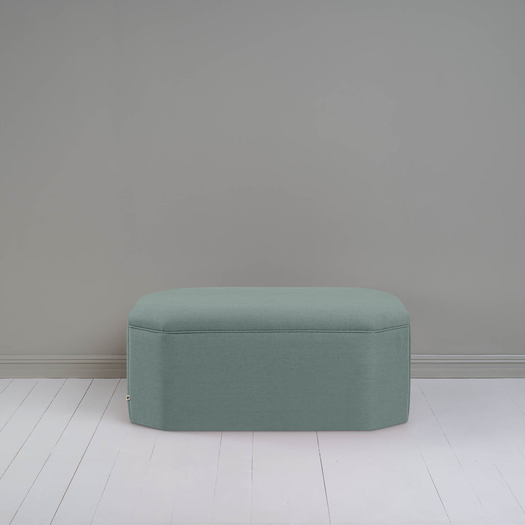 Blue ottoman against gray wall in room.