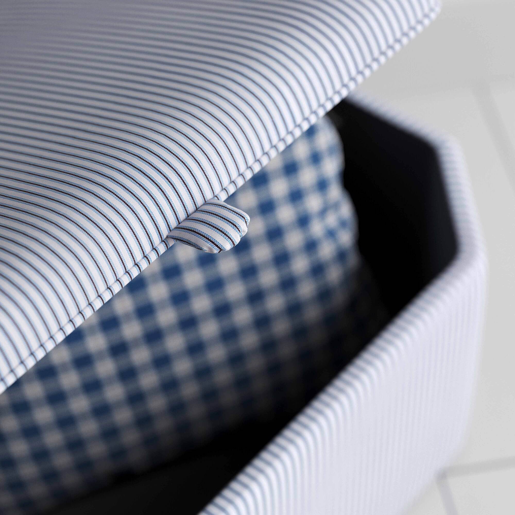A close up of white and blue striped ottoman on a wooden floor, providing a stylish and practical storage solution.