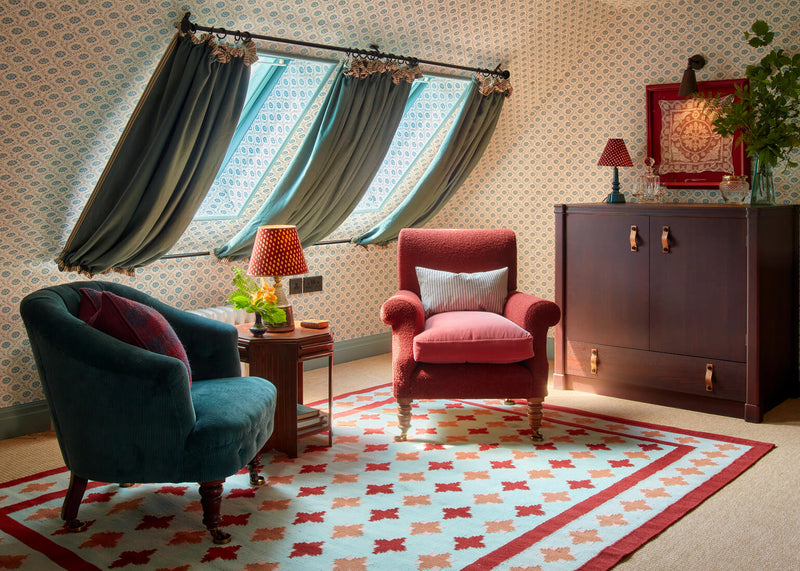 A beautifully designed room by Nicola Harding & Co., featuring two chairs, a side table with a lamp, and elegant wallpaper.