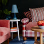 Ditsy Tall Tapered Lamp Shade in Dotty Sky Blue, With Ditsy Ceramic Table Lamp Base in Turquoise, On White Spindle Side Table, Next to an Armchair and a Sofa - Nicola Harding