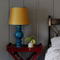 Humbug Straight Empire Paper Lamp Shade in Mustard with Blue Trim, With Hourglass Ceramic Table Lamp Base in Blue, On a Ready Steady Tray Table, Berry Red Bed Side Table - Nicola Harding