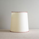 White lamp with red stitching detail, adding a pop of color to the sleek design.
