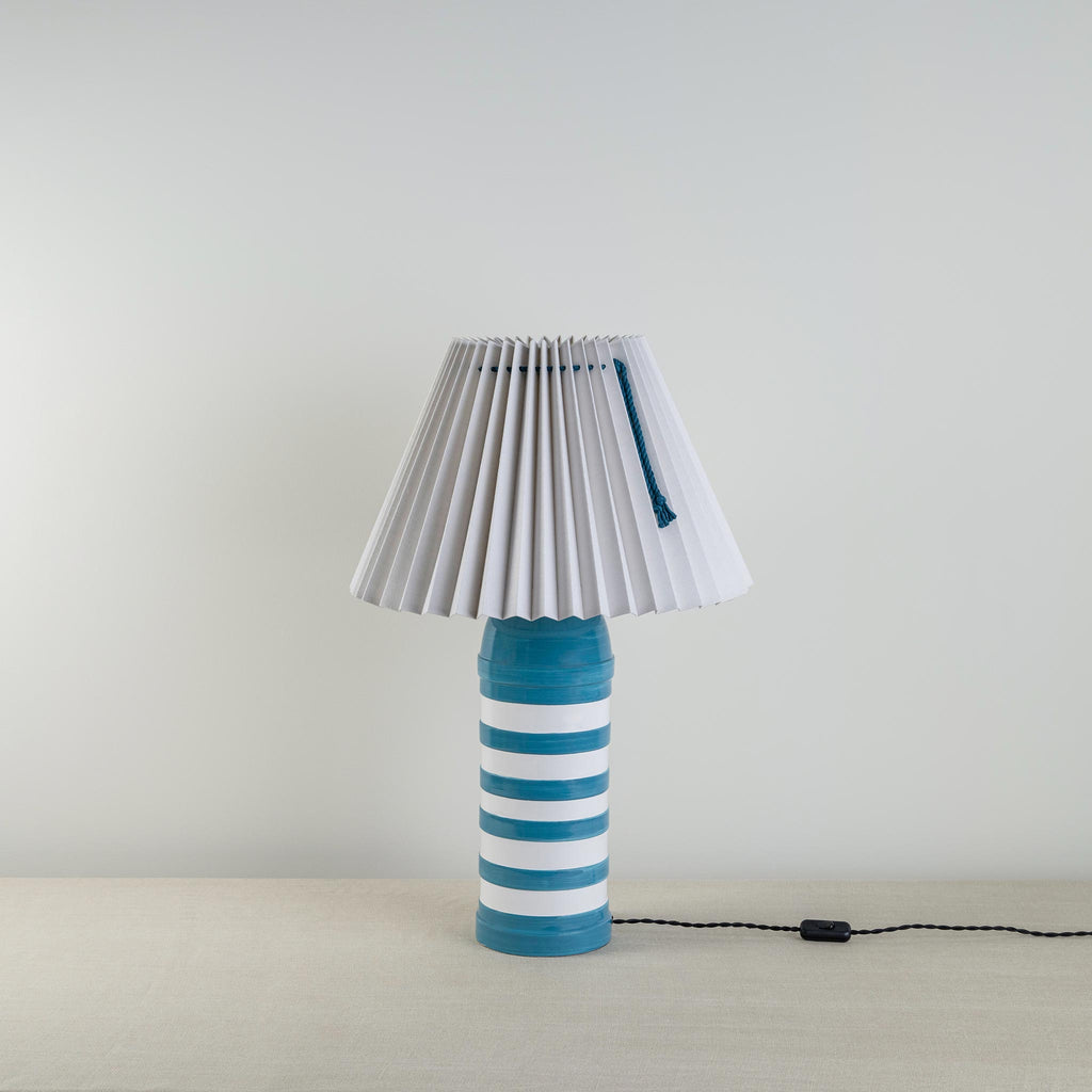 Humbug Striped Ceramic Table Lamp Base in Blue & Warm White, With Sunburst Concertina Natural Pleat Lamp Shade with Peacock Blue Cord - Nicola Harding