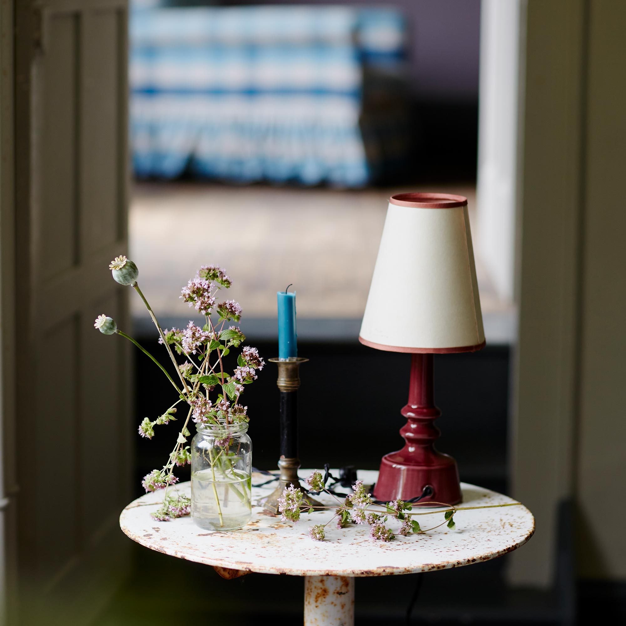 Ditsy Ceramic Table Lamp Base in Damson Pink, With Bright Spark Tall Tapered Paper Lamp Shade in Soft White, a Candle and Bunch of Flowers - Nicola Harding