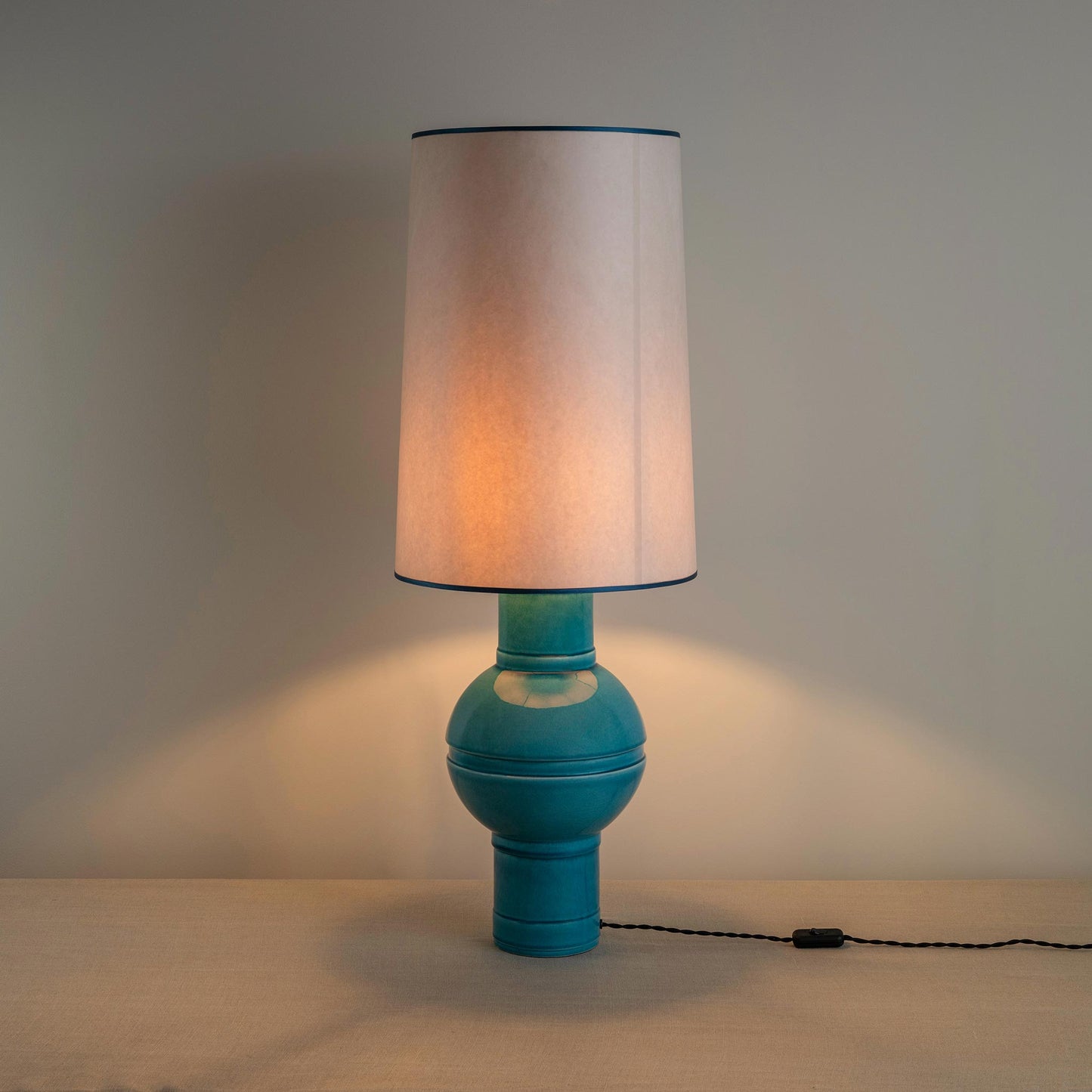 Orb Ceramic Table Lamp Base in Turquoise, With Whimsical Tall Straight Empire Lamp Shade in Soft White with Peacock Blue Trim, With Lights 'ON' - Nicola Harding