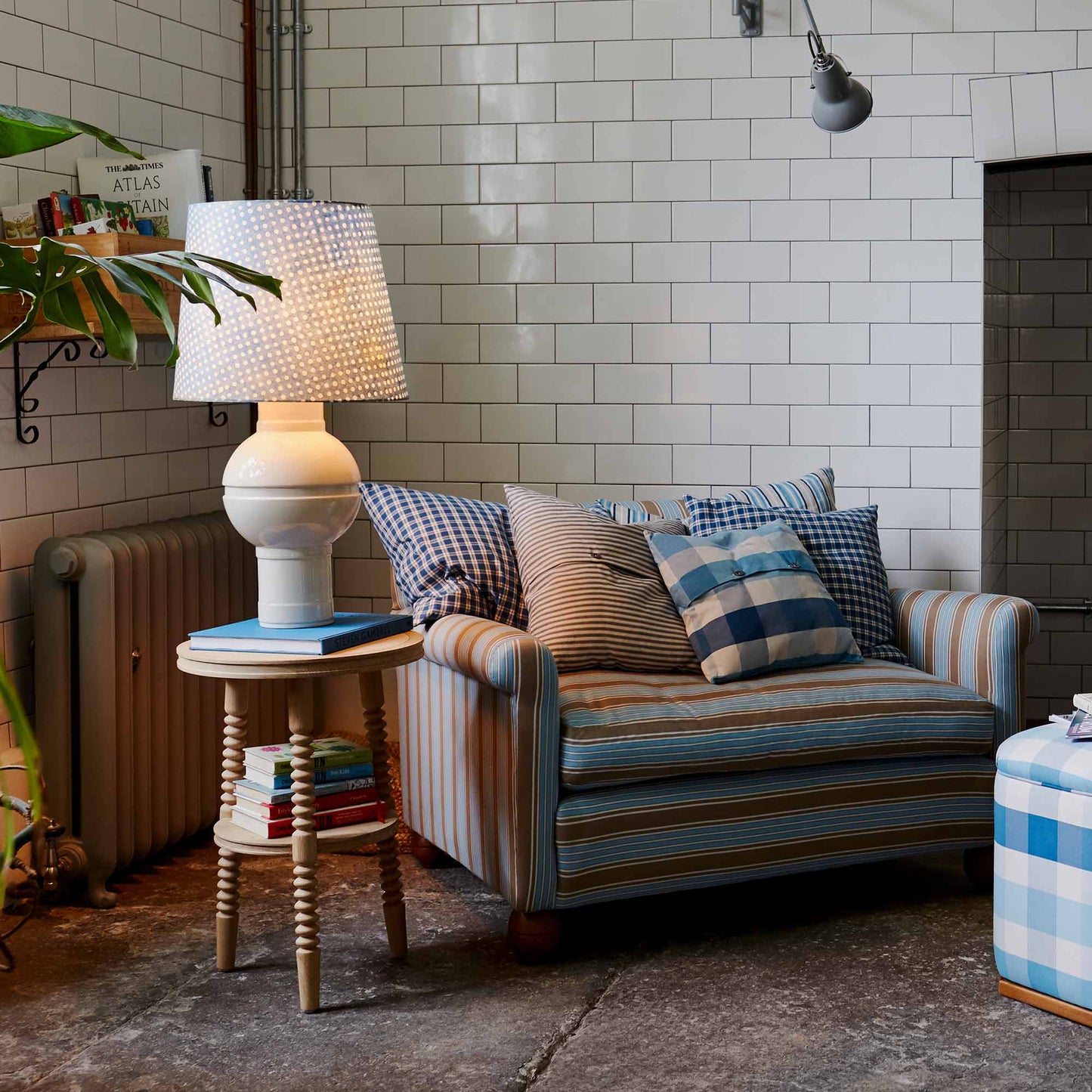 Orb Ceramic Table Lamp Base in Warm White, With Humbug Straight Empire Batik Paper Lamp Shade in Dotty Sky Blue, On a Side table Next to a Loveseat With Cushions - Nicola Harding