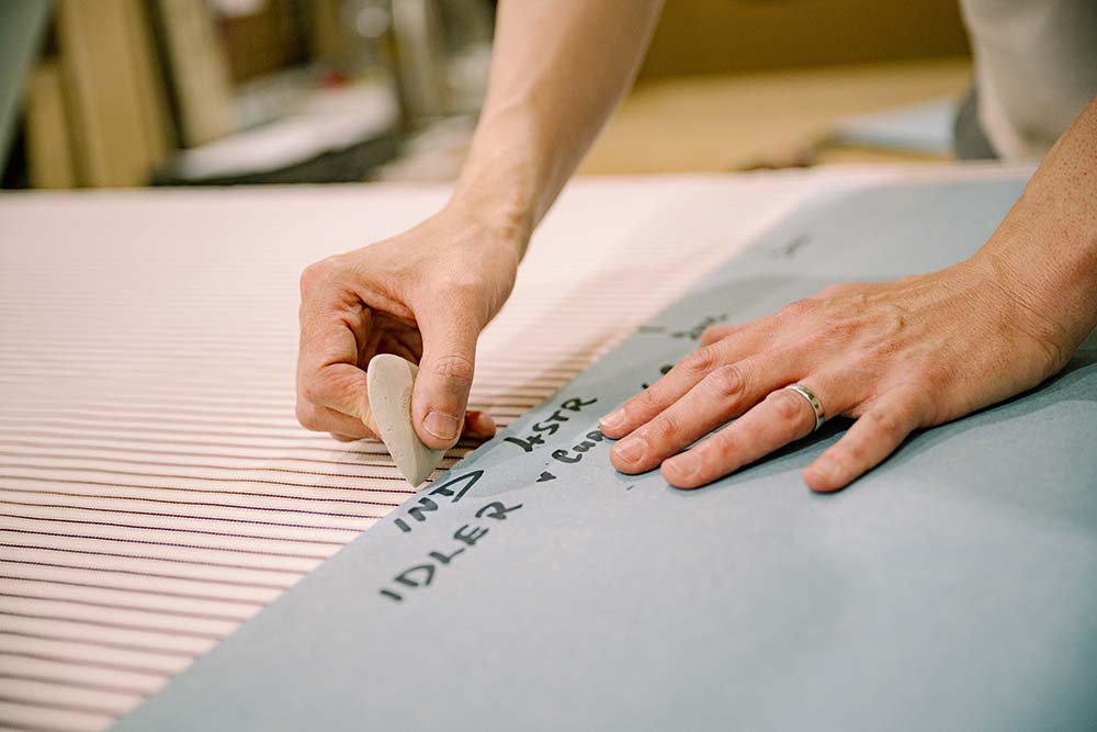Man preparing fabric for cutting at Nicola Harding & Co, highlighting expert craftsmanship.