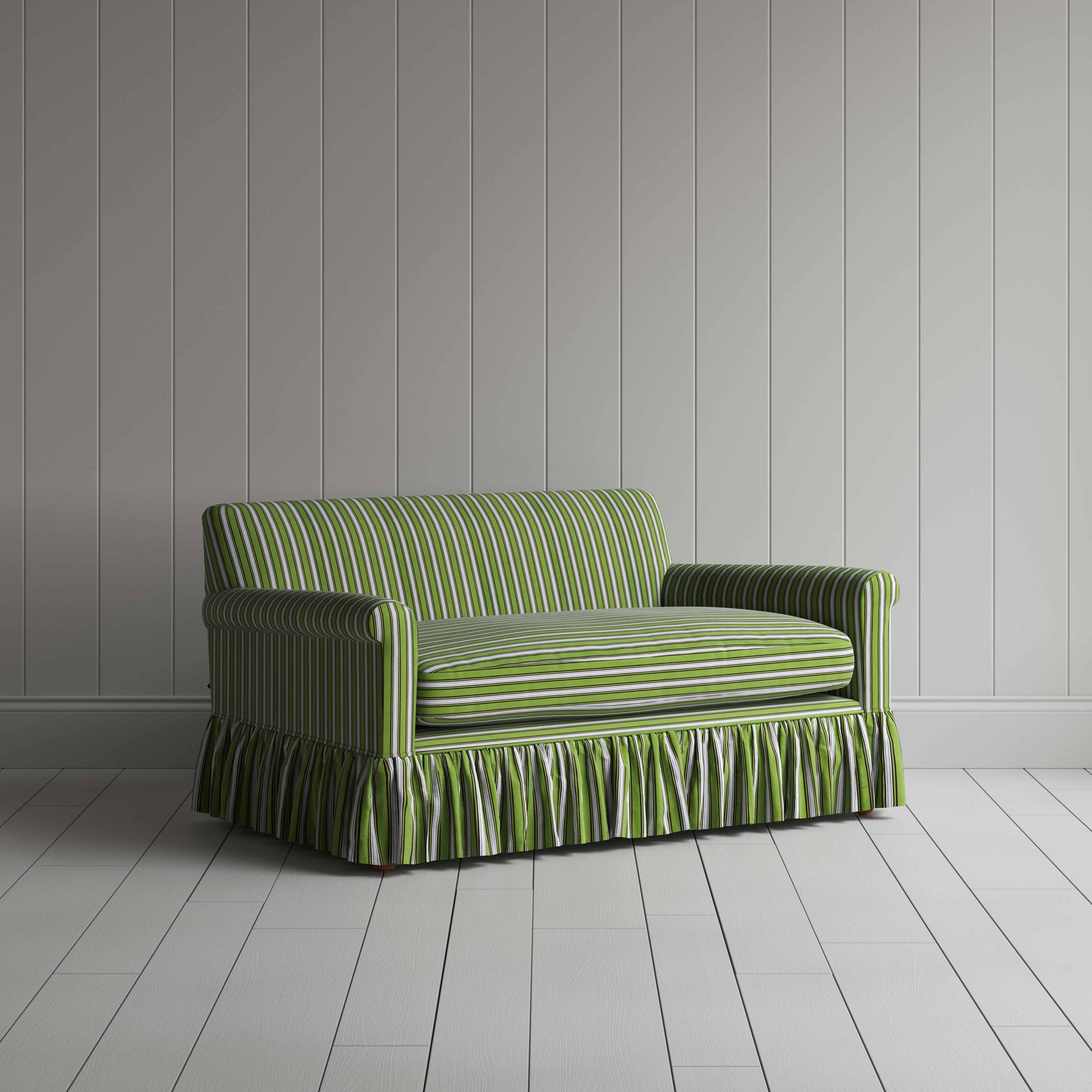  A green and white striped sofa on a wooden grey floor, adding a touch of elegance to the room's decor. 