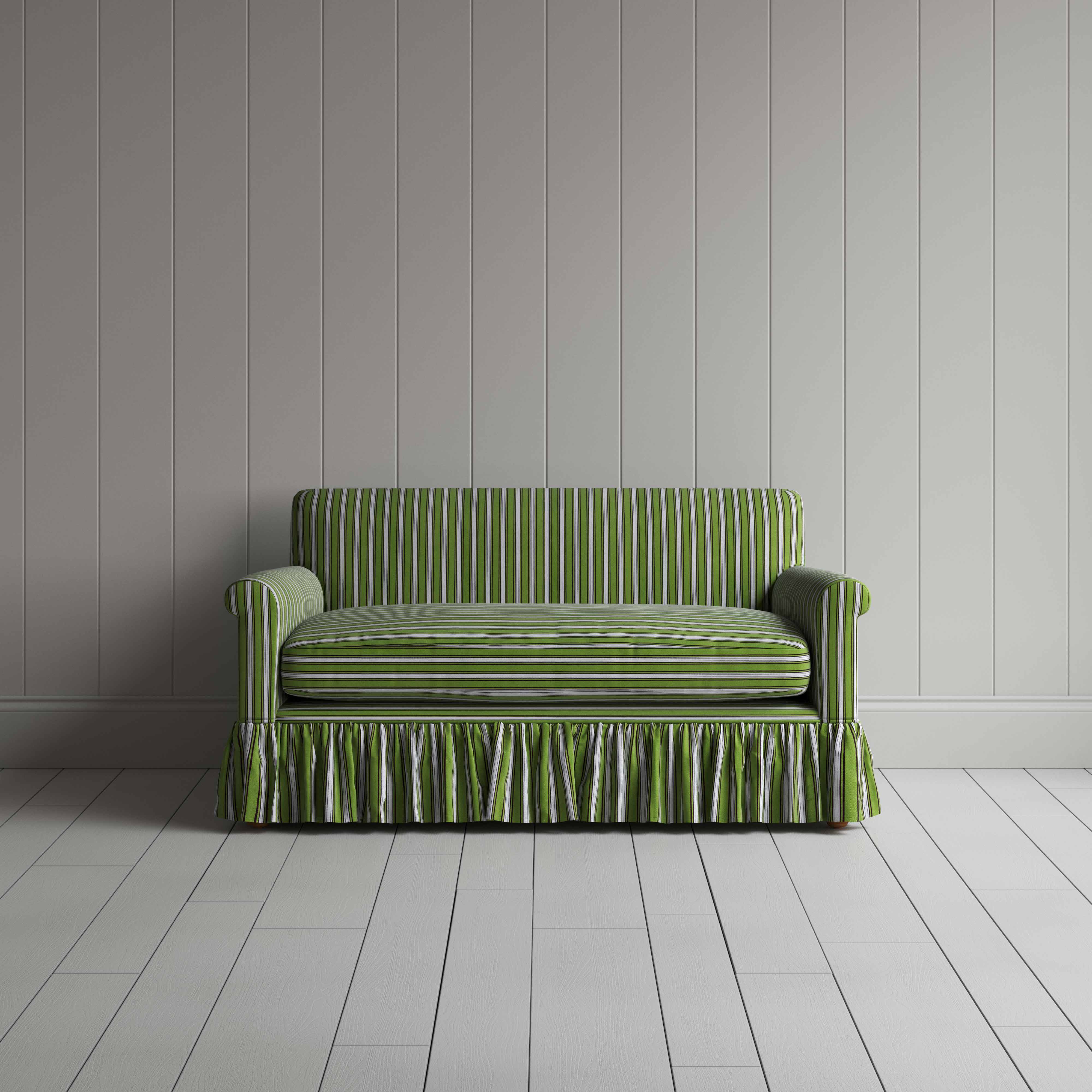  A green couch with a ruffled skirt placed in front of a grey wall. 