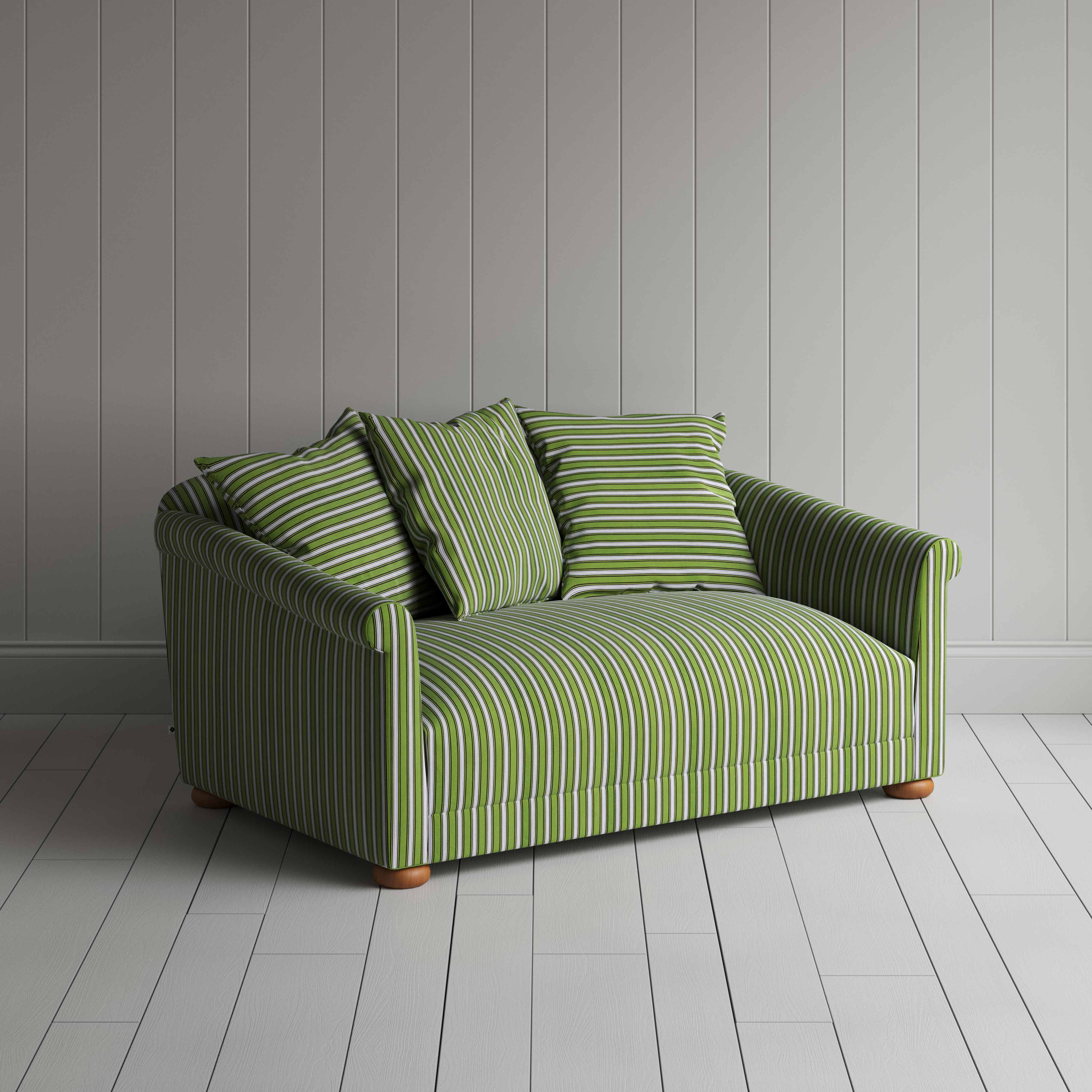  A green and white striped couch on a wooden floor, adding a touch of elegance to the room's decor. 