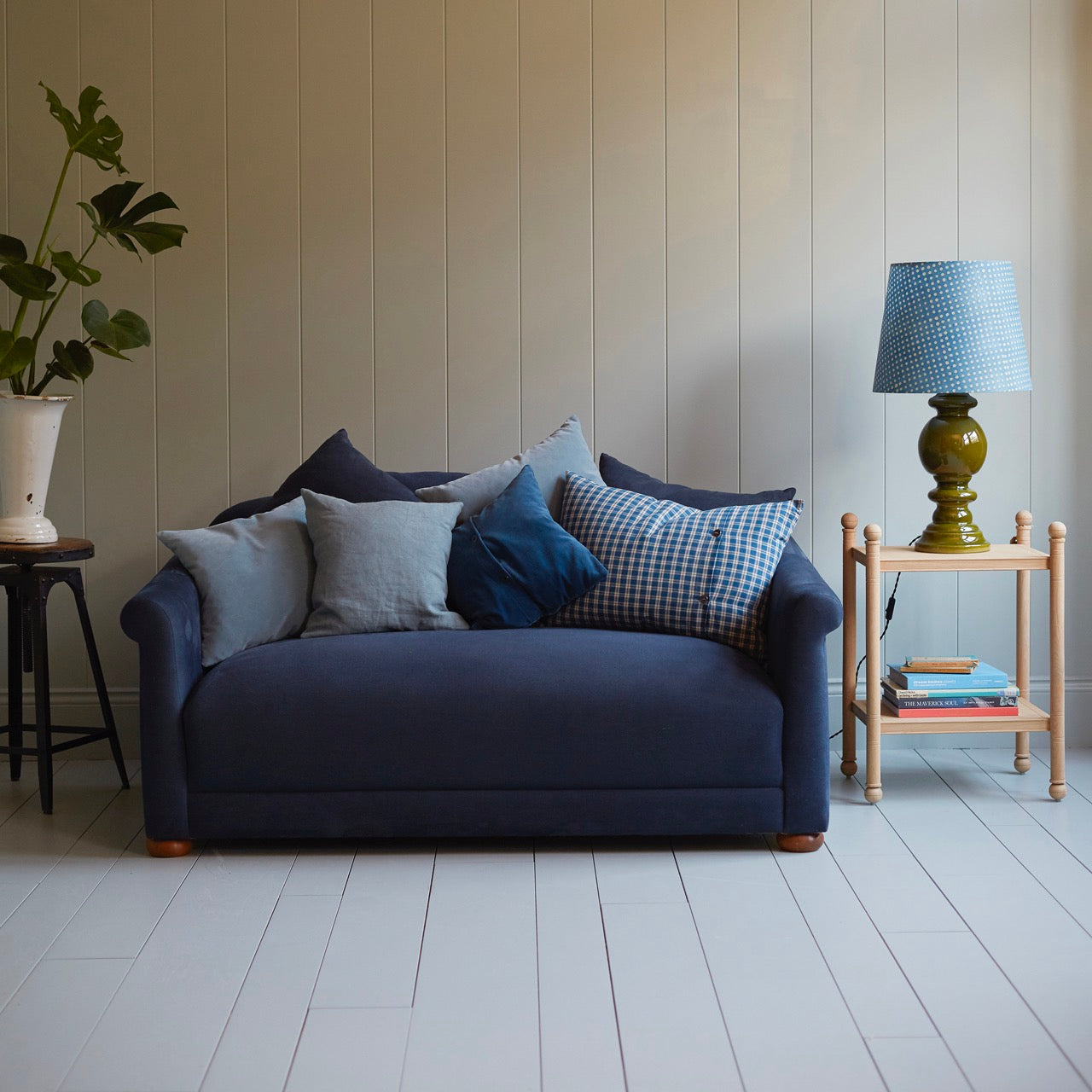  A blue couch with patterned pillows and a matching lamp, creating a cozy and stylish seating area. 