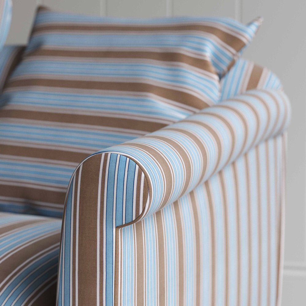 A close up of blue and white striped sofa on wooden floor.