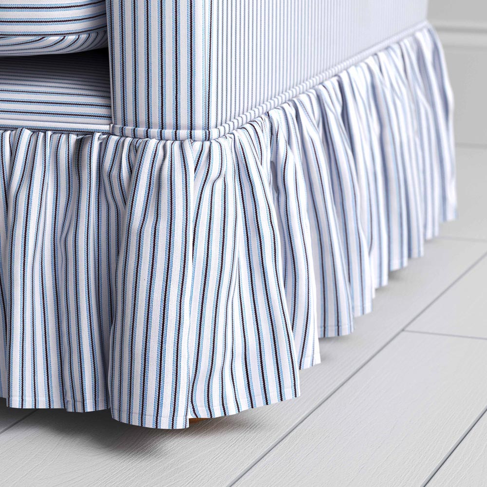 A close-up of a blue and white striped sofa skirt, adding a touch of elegance to the bedroom decor.