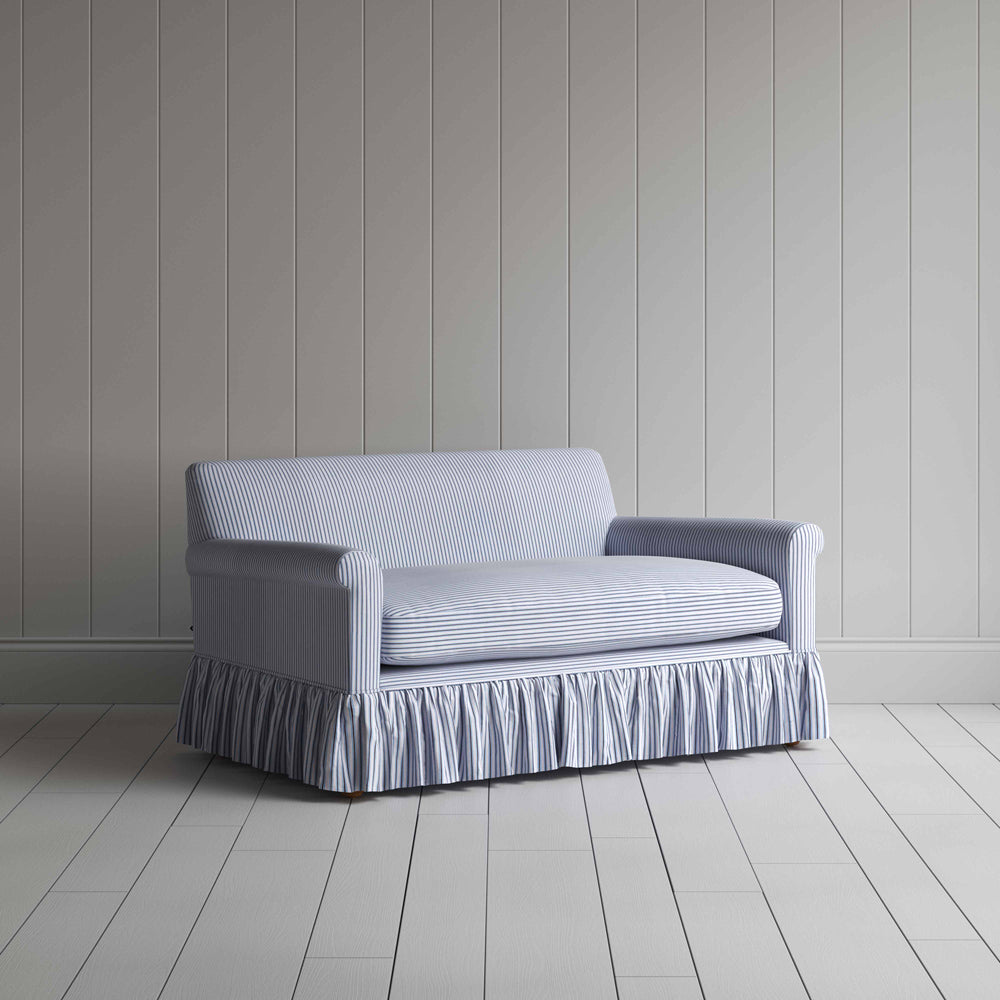 Stylish grey couch with ruffled skirt on wooden floor.