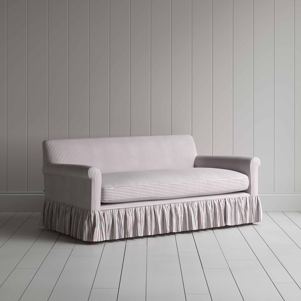  Stylish greyish brown couch with ruffled skirt on wooden floor. 