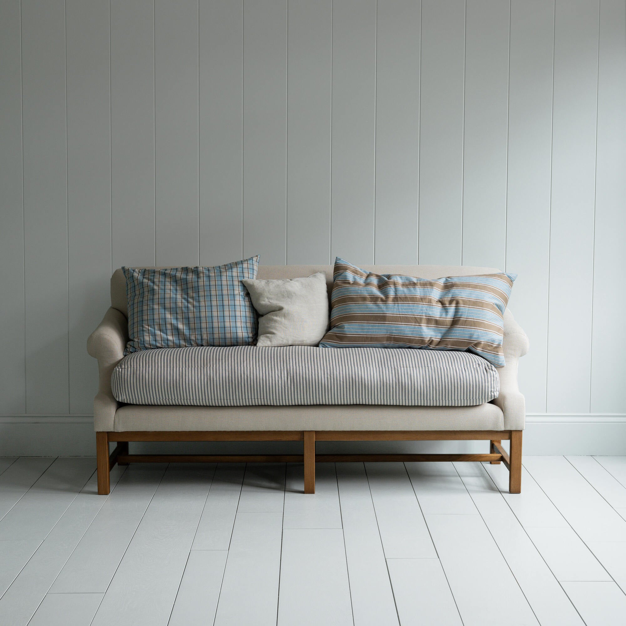  White couch on wooden floor in minimalist living room. 