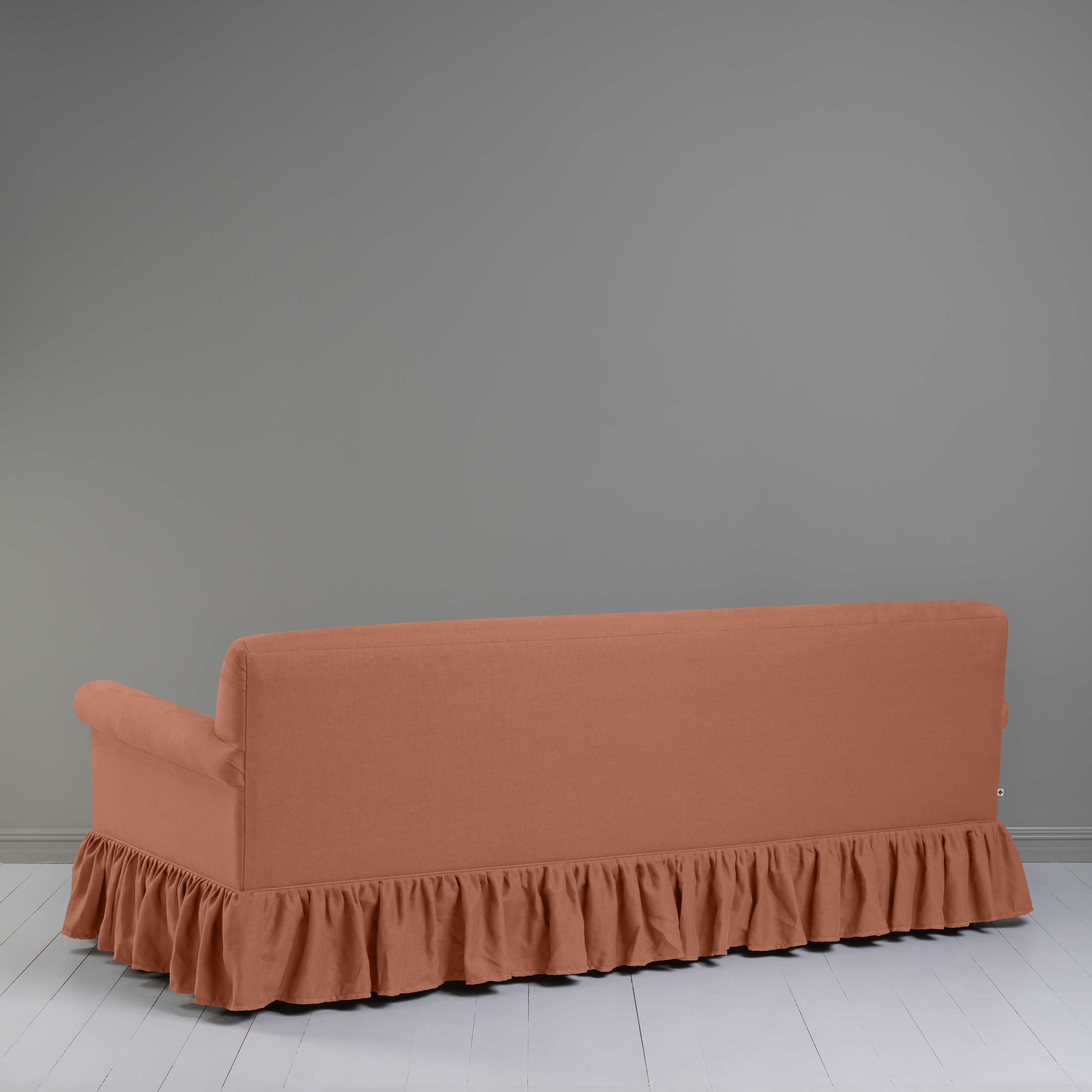  A sofa with a ruffled skirt placed on a white floor, creating a cozy and elegant atmosphere. 