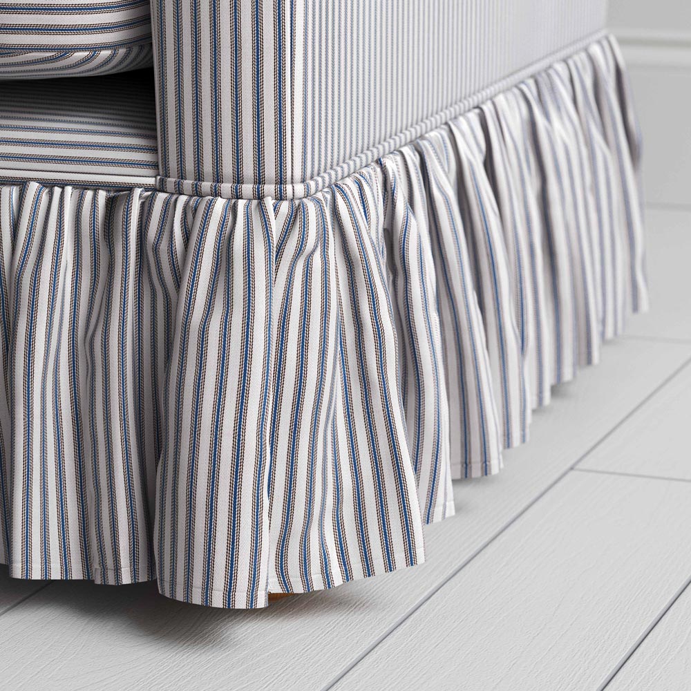  A close-up of a blue and white striped sofa skirt, adding a touch of elegance to the bedroom decor. 