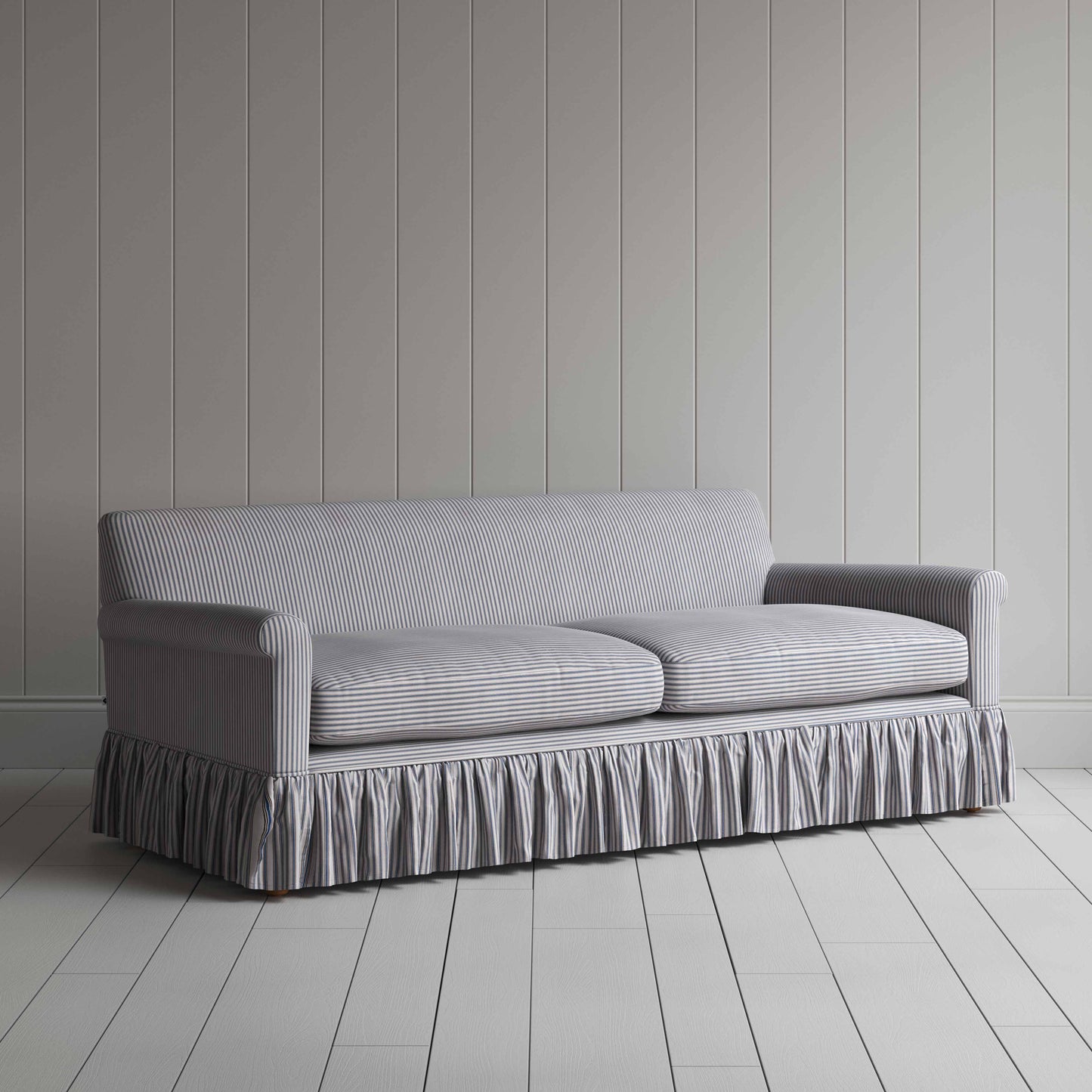 Stylish grey couch with ruffled skirt on wooden floor.