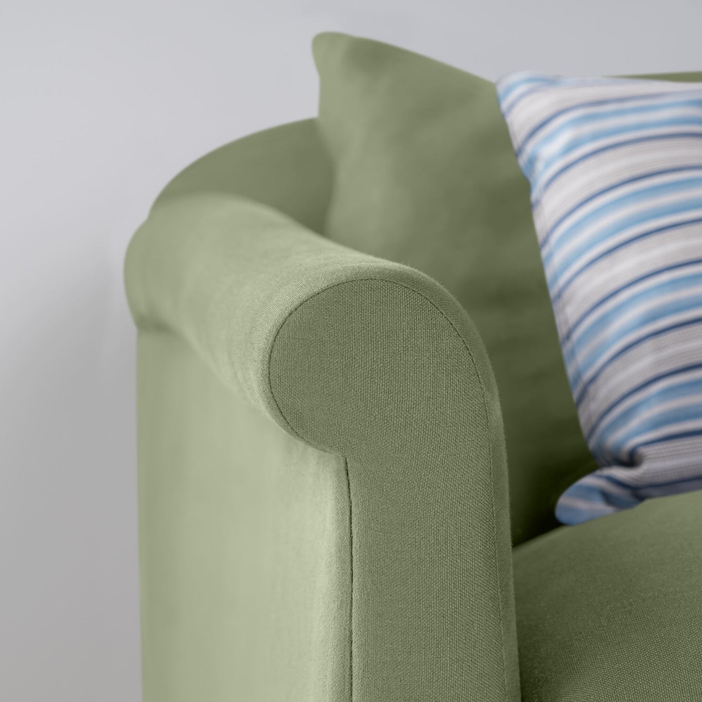 A close-up of a green sofa with a blue and white striped pillow, creating a cozy and stylish seating arrangement.