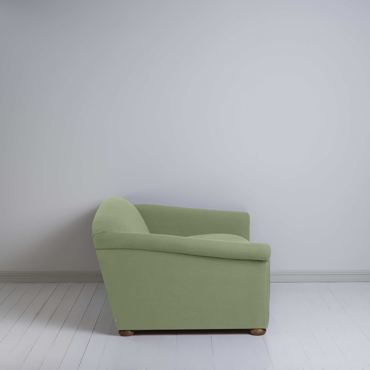 Green couch in a room with white walls.