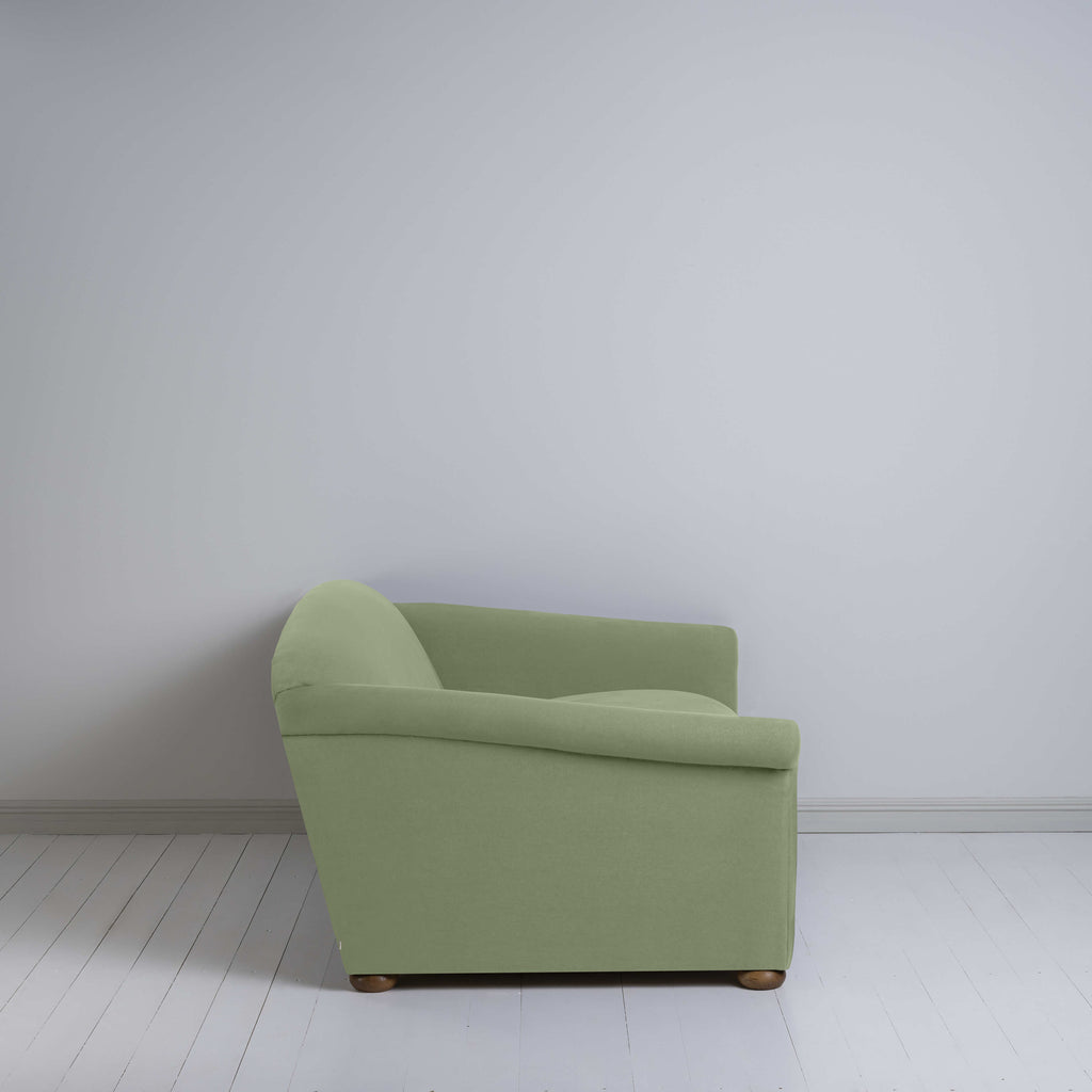  Green couch in a room with white walls. 