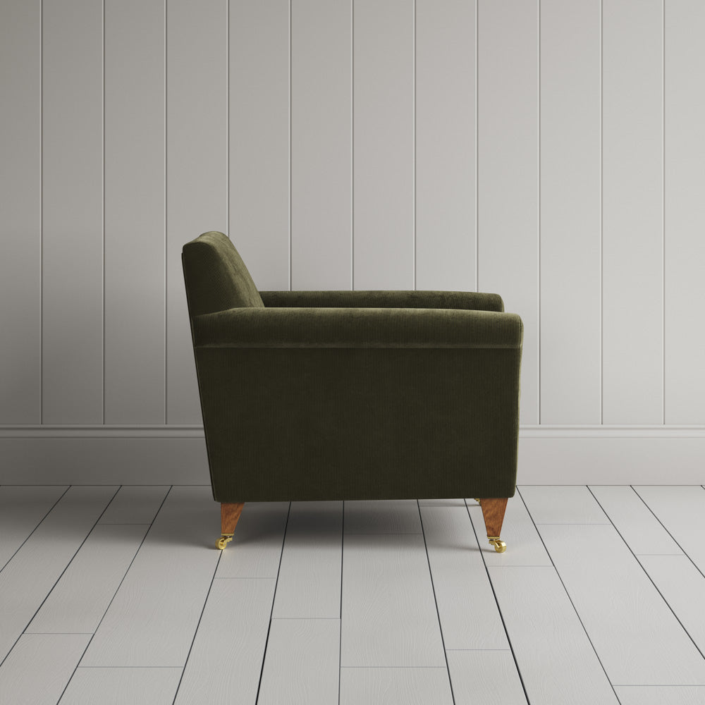  Side profile of the Caper green corduroy Idler armchair, an elegant Edwardian-style occasional chair. 