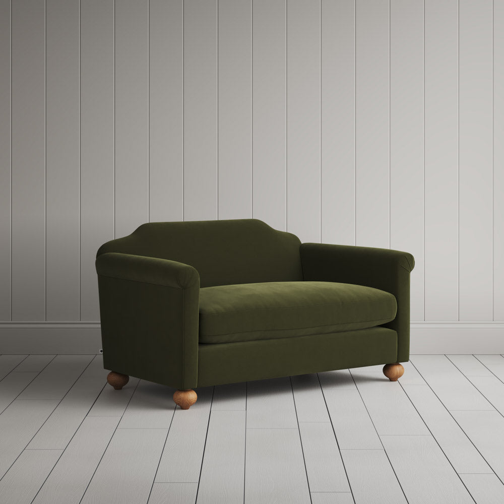 Angled shot of a green upholstered love seats by Nicola Harding.