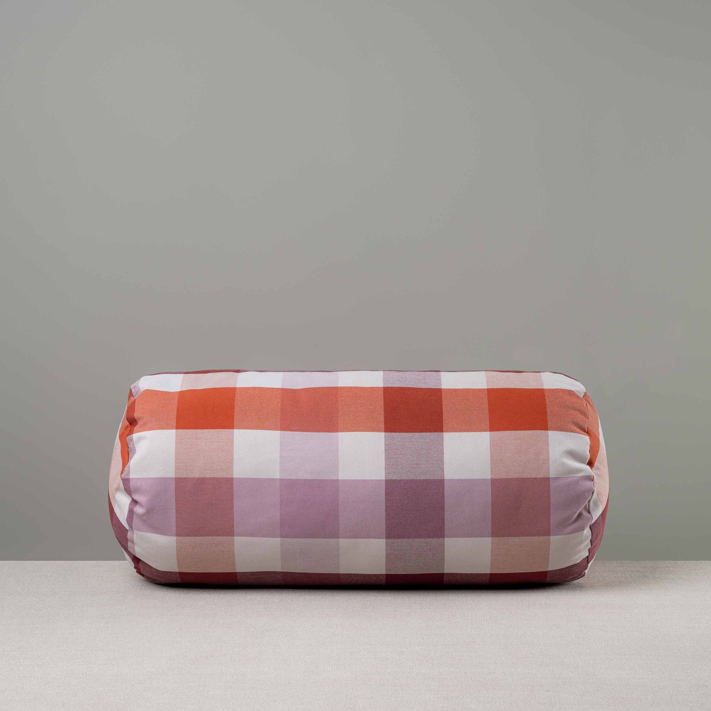 Front View of Bask Bolster Cushion in Checkmate Cotton, Berry - Nicola Harding