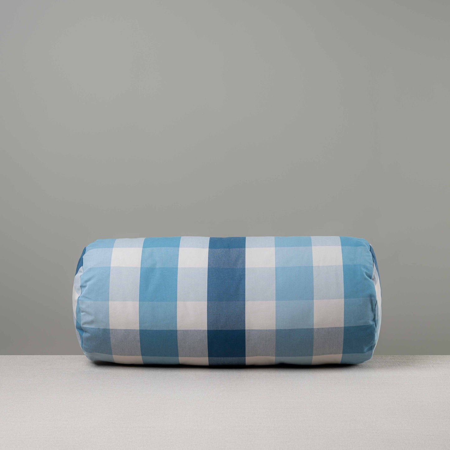 Front View of Bask Bolster Cushion in Checkmate Cotton, Blue - Nicola Harding