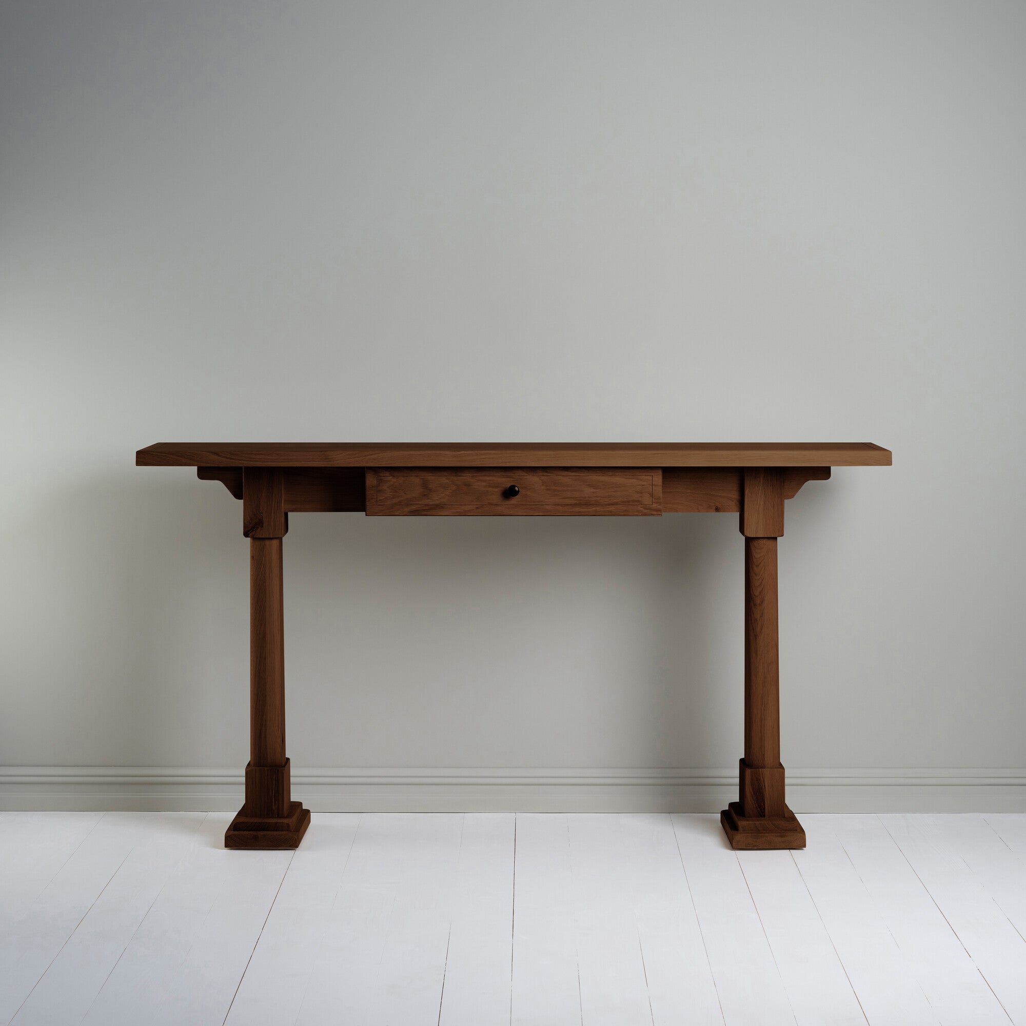  Console Table with a drawer in smoky stained oak, placed against the wall. 